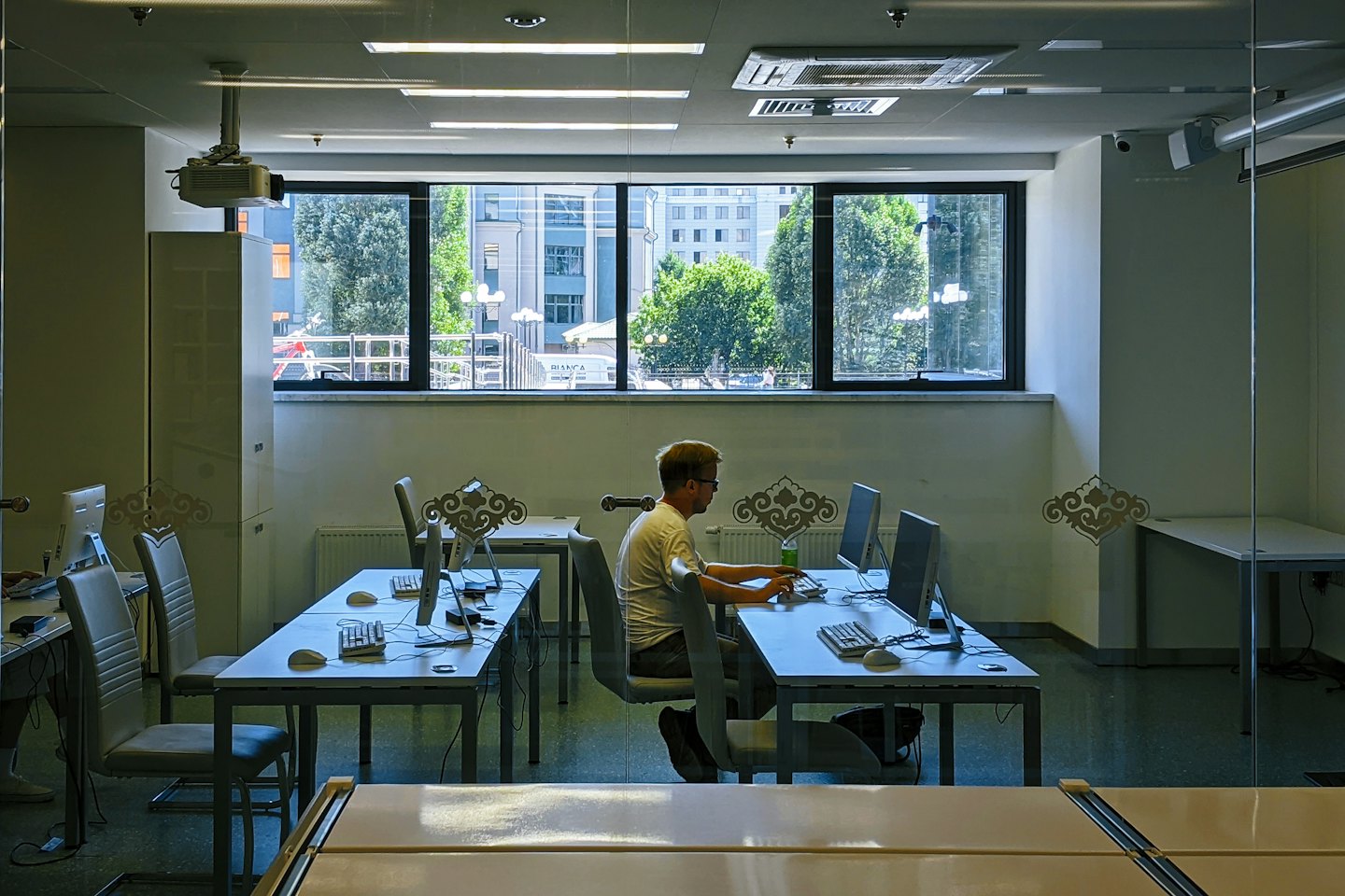 Man wearing a white t-shirt working at a desktop computer.